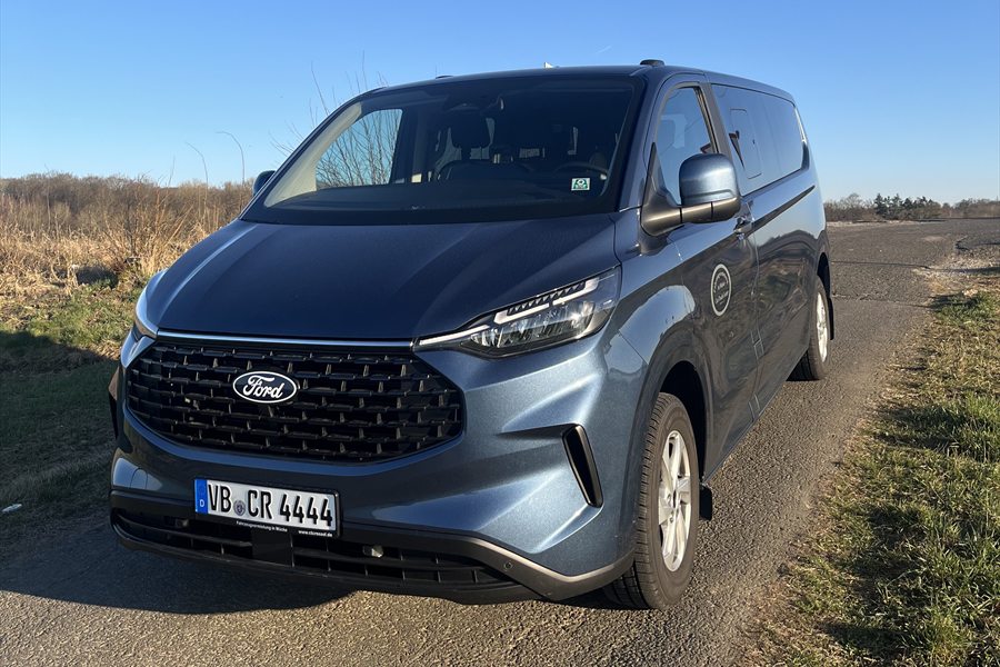 Blauer Ford Transit Custom Kleinbus auf einem Feldweg
